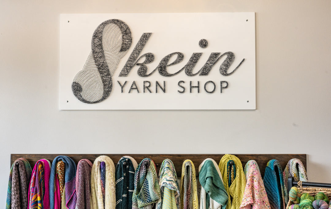 Skein Yarn Shop sign above a display of colorful yarn.
