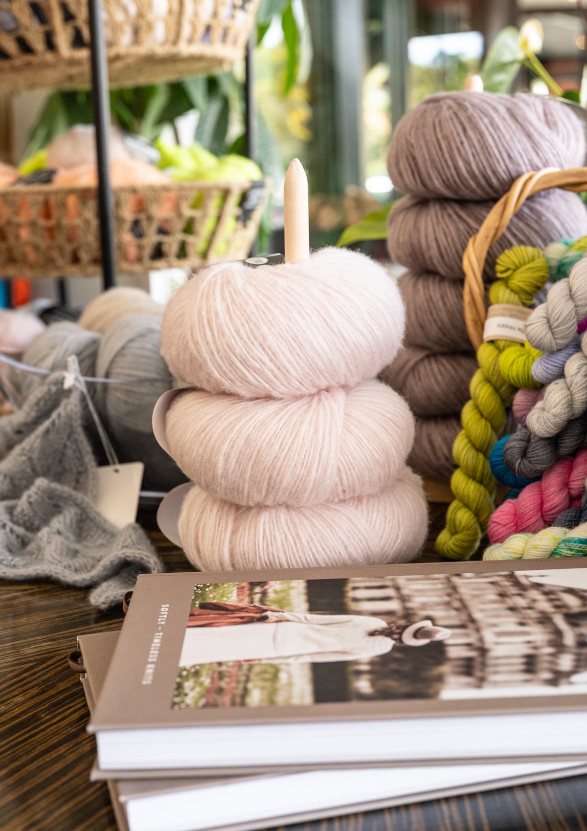 Stacks of yarn in various colors with a book on a table at Skein Yarn Shop