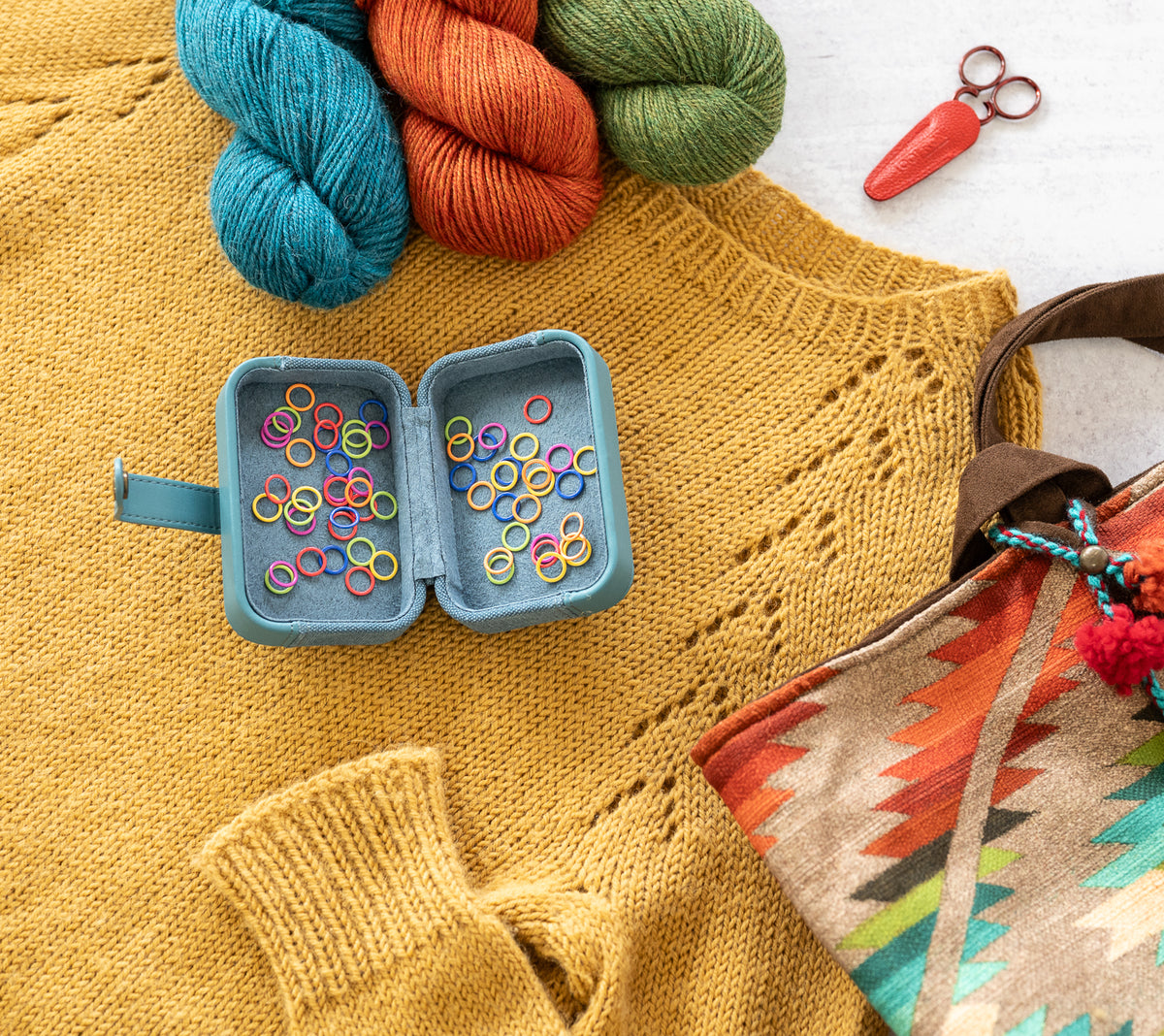 Colorful yarn skeins and knitting accessories on a textured fabric background
