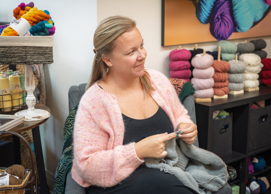Skein store manager Justine knitting inside the yarn shop