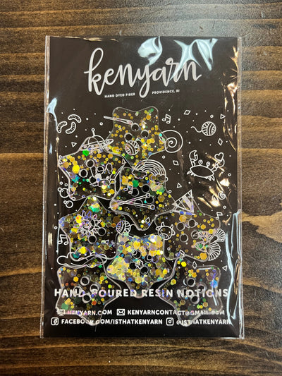 A clear star-shaped resin button with yellow and green glitter embedded in the resin.