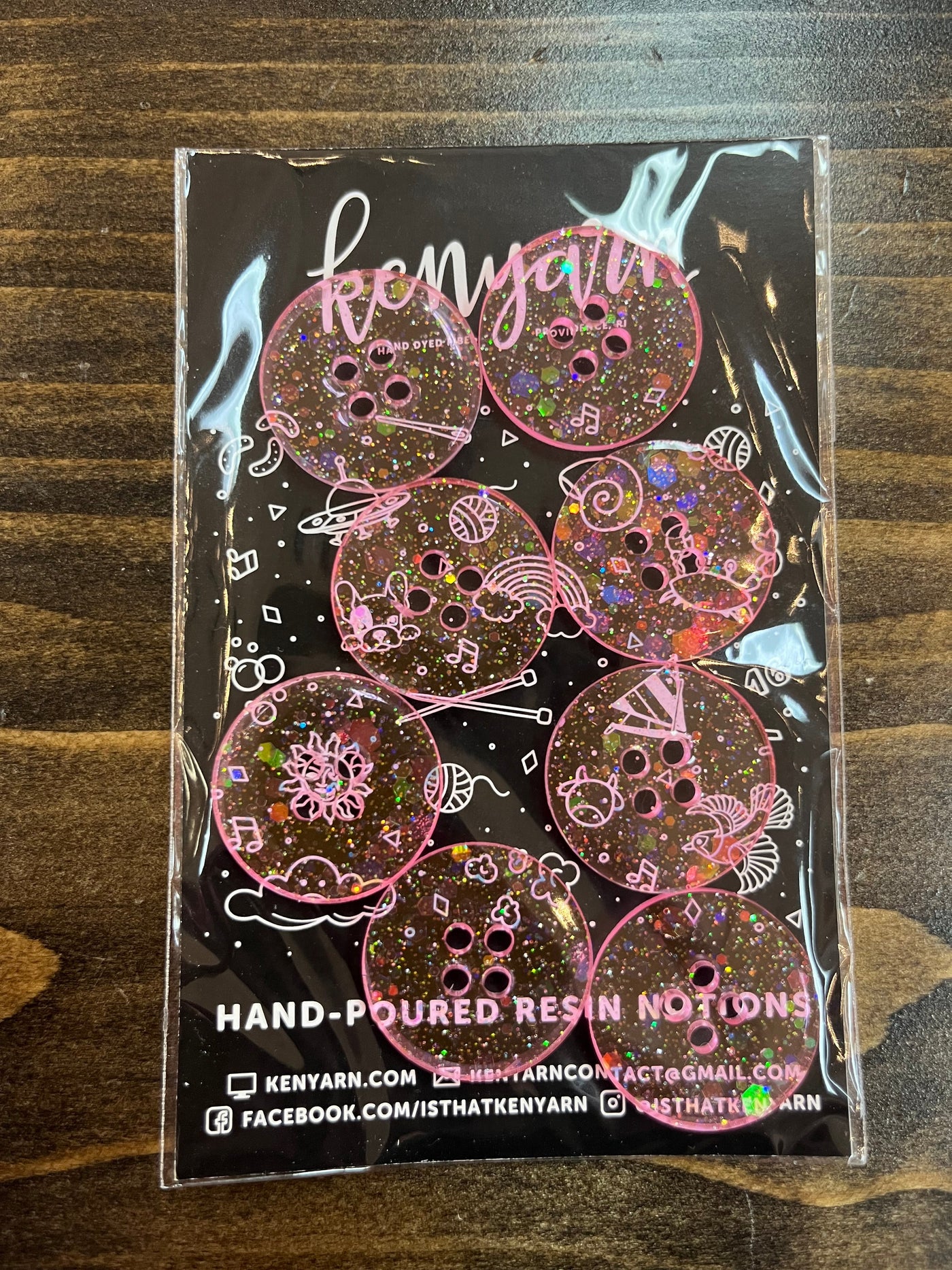  A bright pink 1-inch circle resin button with multi-colored transparent glitter swirling inside. The packaging reads "Kenyarn Hand Poured Resin Button."