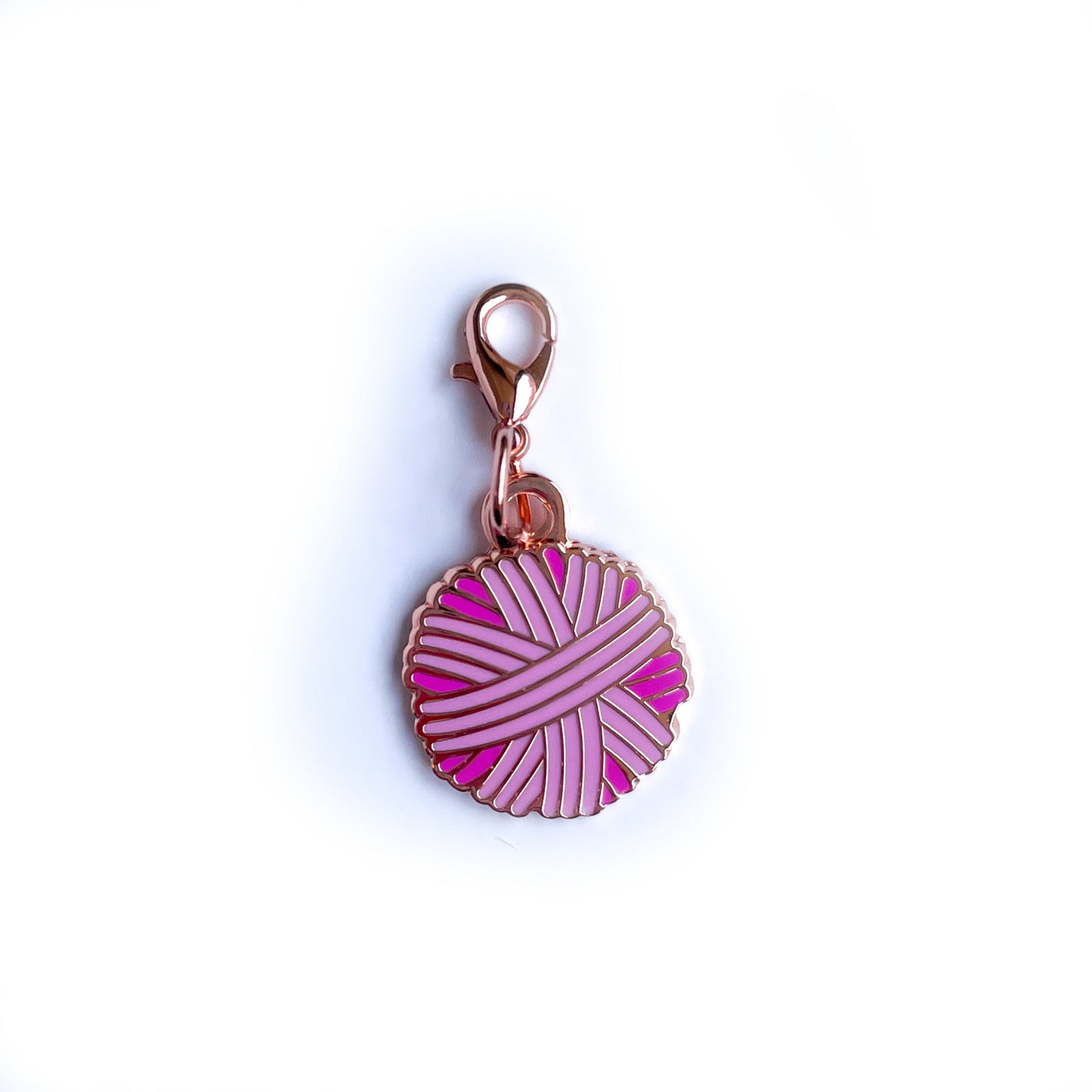 A yarn ball shaped charm in shades of pink with a lobster claw clasp. 