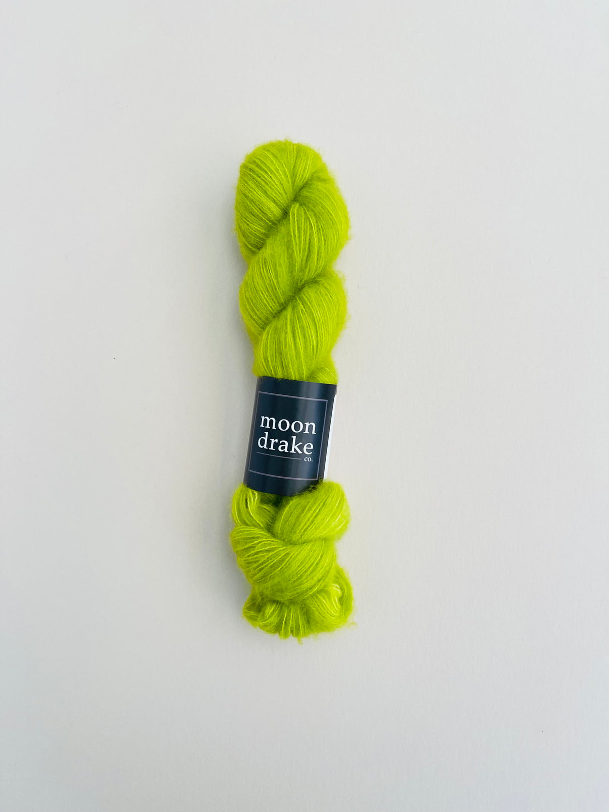 A skein of lime green yarn with a fuzzy halo.