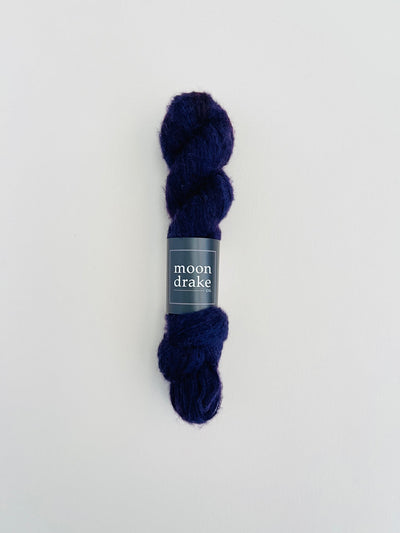 A midnight blue skein of brushed cashmere merino yarn. It has a visible soft halo of texture.
