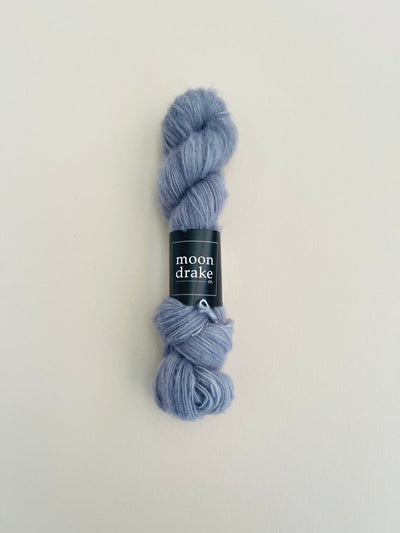 A slate grey skein of fuzzy brushed merino yarn.