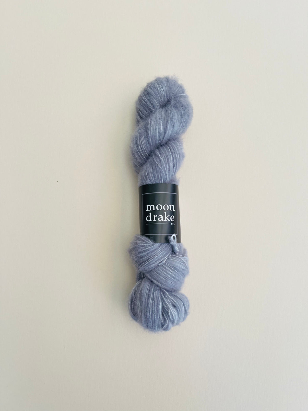 A cool grey skein of fingering weight fuzzy cashmere yarn.