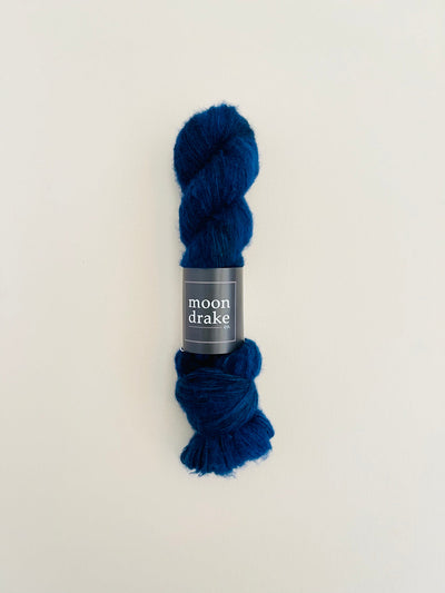 A deep blue skein of yarn with a very fuzzy halo effect due to the floofy nature of the brushed cashmere fiber content.