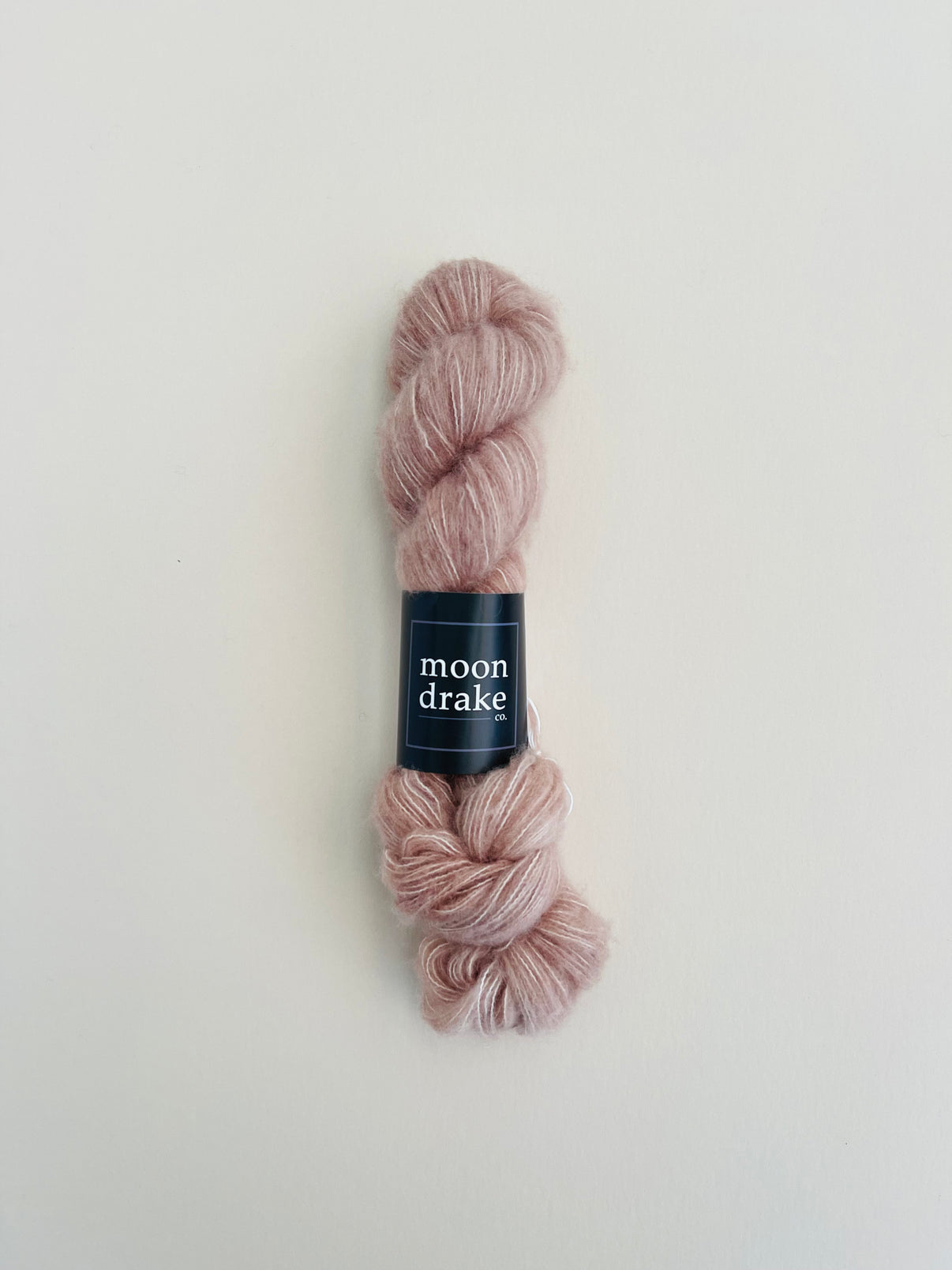 A warm neutral skein of fuzzy fingering weight yarn.