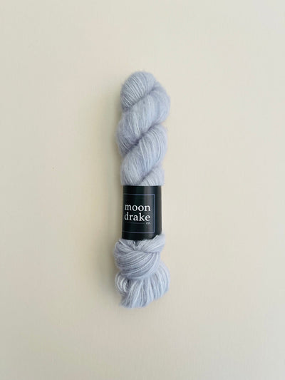 A neutral grey skein of soft fingering weight yarn.