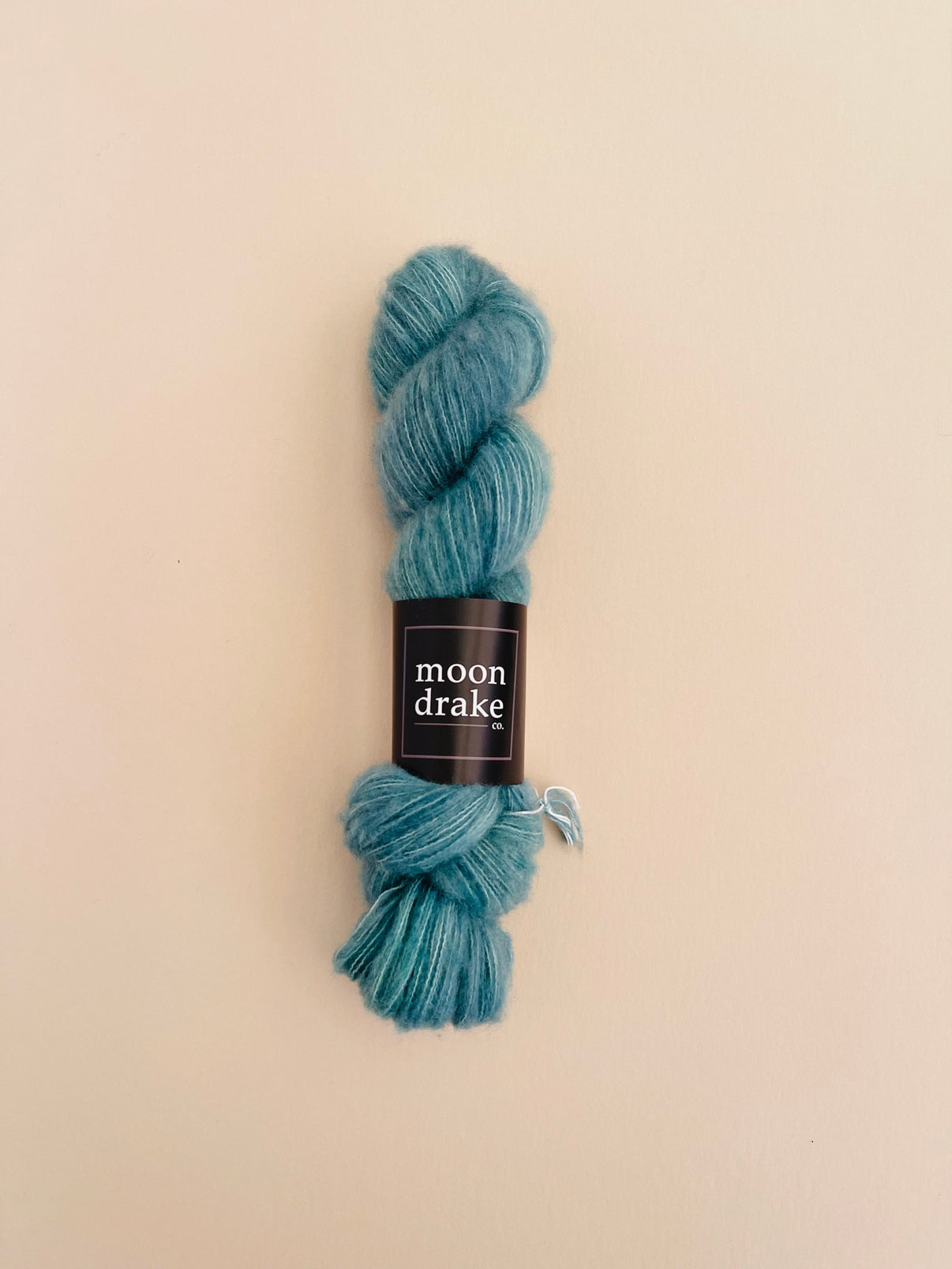 A teal skein of yarn that looks very soft to the touch.
