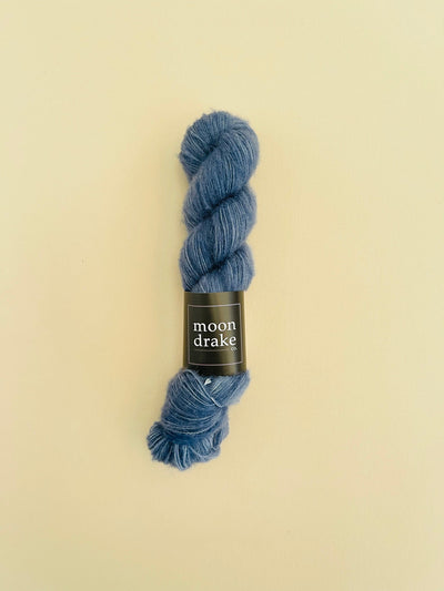 A grey blue skein of yarn with a fuzzy texture.