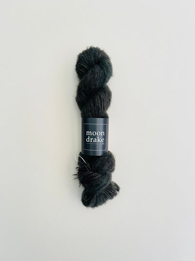 A cool black skein of yarn with a fuzzy halo of brushed cashmere texture.